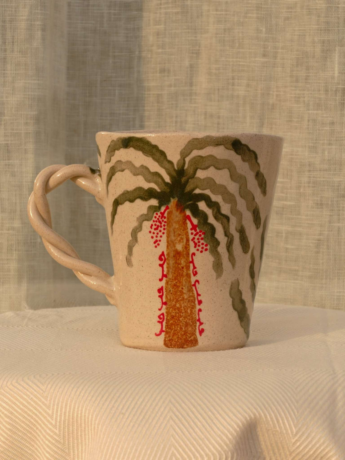 Wheel-thrown ceramic mug with wavy handle and the Arabic word for love