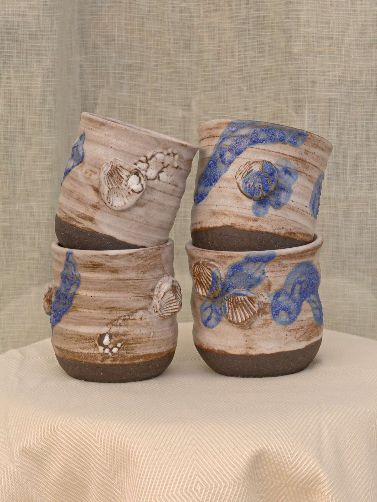 Set of two black clay cups with crawling glaze and seashell imprint