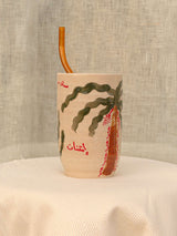 Wheel-thrown ceramic tumbler with palm trees and Arabic calligraphy
