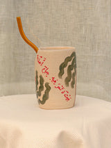 Wheel-thrown ceramic tumbler with palm trees, Arabic calligraphy and a glass straw