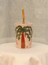 Wheel-thrown ceramic tumbler with palm trees, Arabic calligraphy and a glass straw