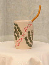 Wheel-thrown ceramic tumbler with palm trees, Arabic calligraphy and a glass straw